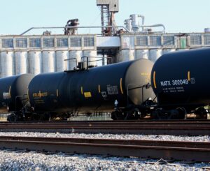 Tank Rail Cars on a track with industrial buildings in the background on a clear day. This is an example image of the type of confined space the employees may have dealt with.